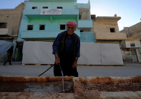 A kurdish man is seen in front of "Democratic Community Academy" in Aleppo's Sheikh Maqsoud neighbourhood, Syria July 15, 2017. REUTERS/Omar Sanadiki