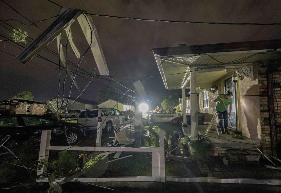 A woman is seen sweeping her neighbor’s porch, which was damaged due to a tornado.