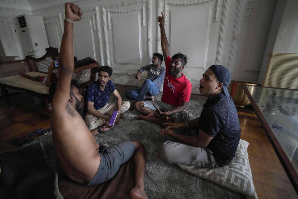 Protesters shout slogans as they stay and play cards in prime minister's official residence a day after it was stormed in Colombo, Sri Lanka, Sunday, July 10, 2022. Sri Lanka’s president and prime minister agreed to resign Saturday after the country’s most chaotic day in months of political turmoil, with protesters storming both officials’ homes and setting fire to one of the buildings in a rage over the nation's severe economic crisis.(AP Photo/Eranga Jayawardena)