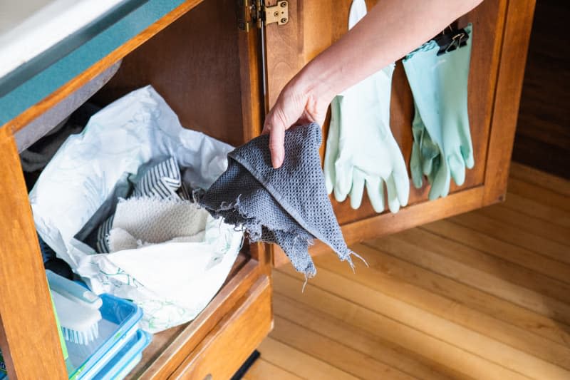 Someone putting used cloth rags into plastic bag.