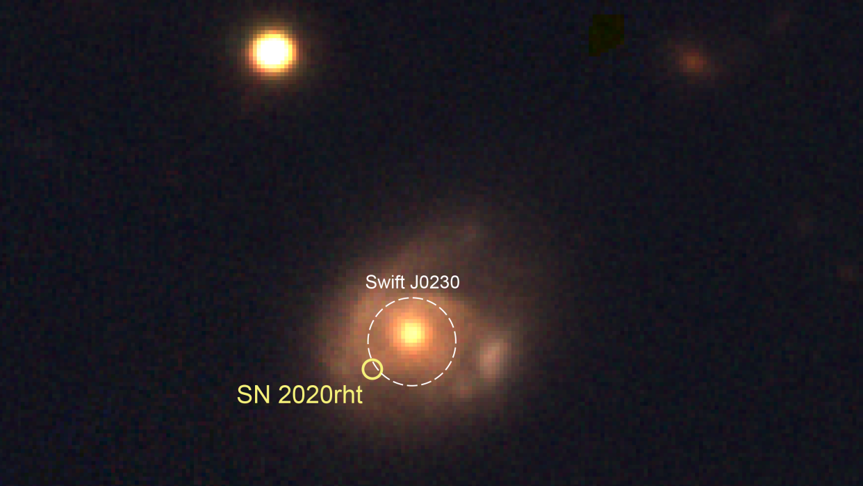  A blurry central circle shines orange/yellow amidst a cloudy haze. A white circle indicates the orb as black hole swj0230. Two additional orbs are in the upper portion of the photo. 