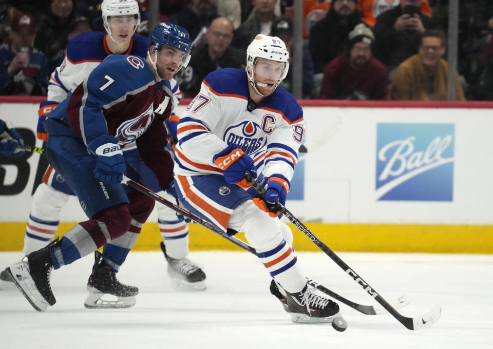 Edmonton Oilers center Connor McDavid, right, looks to pass the puck as Colorado Avalanche defenseman Devon Toews (7) pursues in overtime the third period of an NHL hockey game Sunday, Feb. 19, 2023, in Denver. (AP Photo/David Zalubowski)