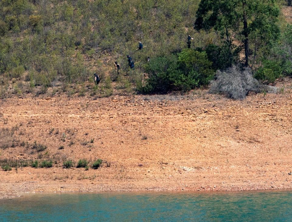 Police officers are seen at the site of a remote reservoir where a search was underway for evidence related to the disappearance of Madeleine McCann (REUTERS)
