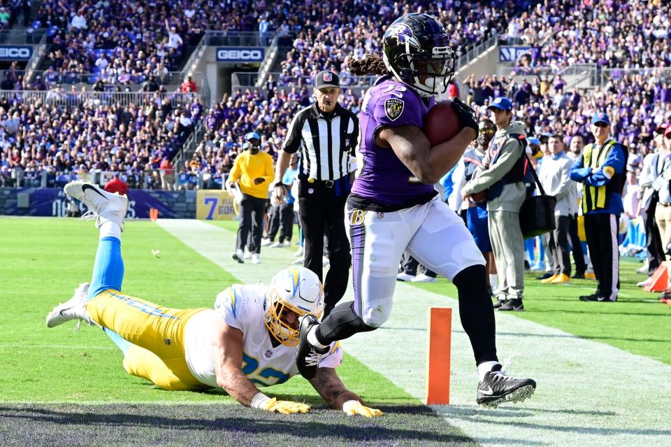 Ravens running back Devonta Freeman leaps past Chargers defensive end Joe Gaziano for a touchdown in the second half.