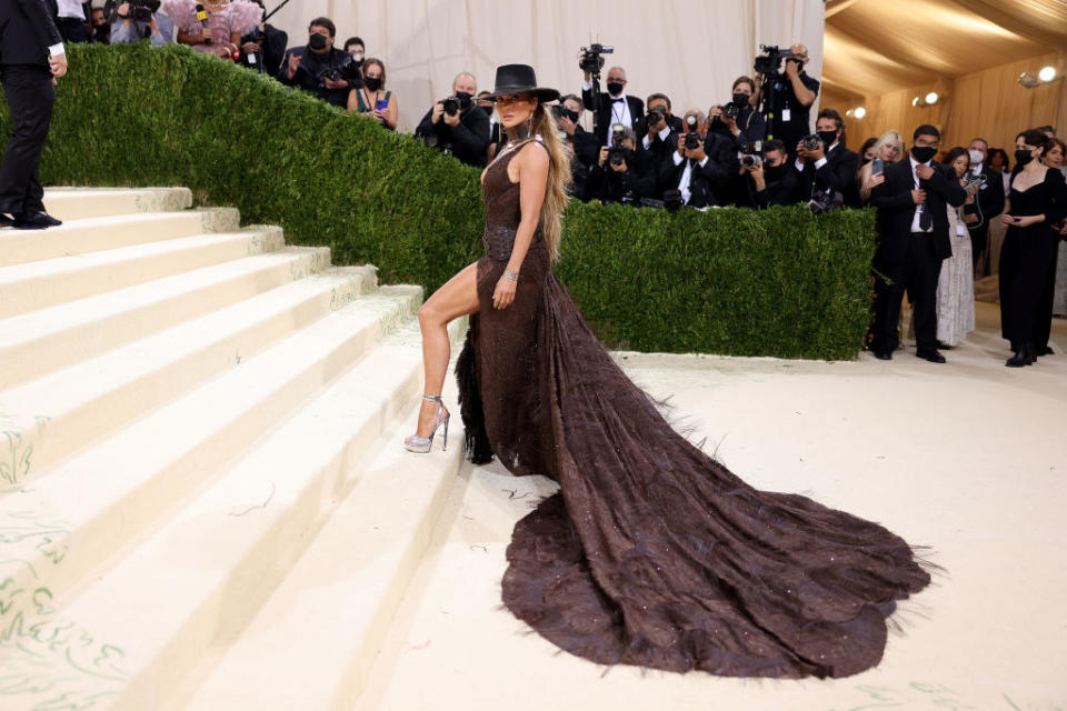 Jennifer Lopez attends The 2021 Met Gala in a long gown with a Western style belt and Stetson hat