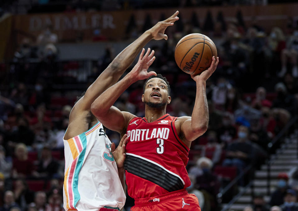 Portland Trail Blazers guard CJ McCollum, right, shoots over San Antonio Spurs forward Keldon Johnson during the second half of an NBA basketball game in Portland, Ore., Thursday, Dec. 2, 2021. (AP Photo/Craig Mitchelldyer)