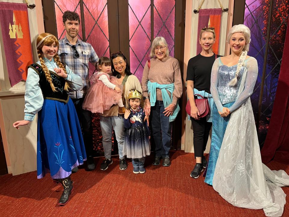 Three women, a man, and two small children pose with Anna and Elsa from "Frozen."