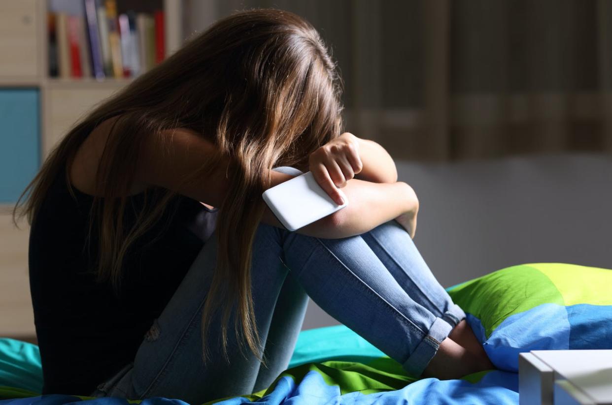 <span class="caption">Technology plays a major role in violence against women and girls.</span> <span class="attribution"><a class="link " href="https://www.gettyimages.com/detail/photo/sad-teen-with-a-phone-in-her-bedroom-royalty-free-image/820379104" rel="nofollow noopener" target="_blank" data-ylk="slk:AntonioGuillem/iStock via Getty Images;elm:context_link;itc:0;sec:content-canvas">AntonioGuillem/iStock via Getty Images</a></span>