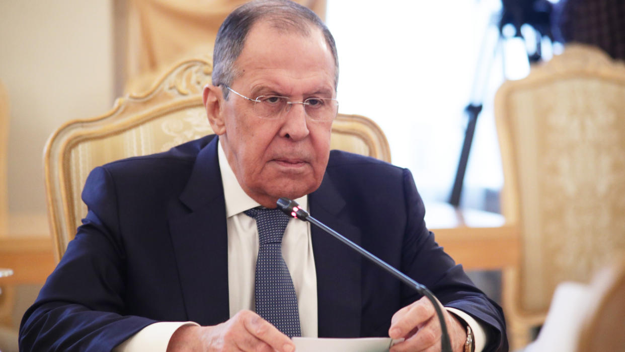Foreign Minister Sergey Lavrov, in front of the miscrophone, stares fixedly at an interlocutor (not seen) at a conference table.