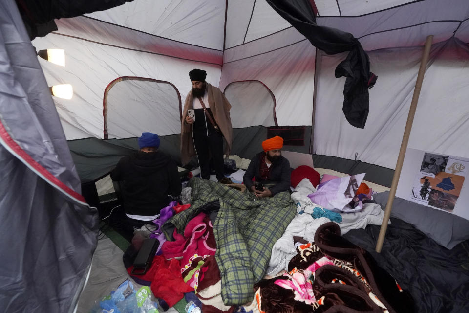 Protesters Manpreet Singh, left, Veer Singh, middle, and Jaypal Singh are camped in a tent outside of the entrance to the Consulate General of India in San Francisco, Monday, March 20, 2023. San Francisco police had erected barriers and parked a vehicle nearby as people protested outside the Consulate General of India to protest the capture of Amritpal Singh. (AP Photo/Jeff Chiu)