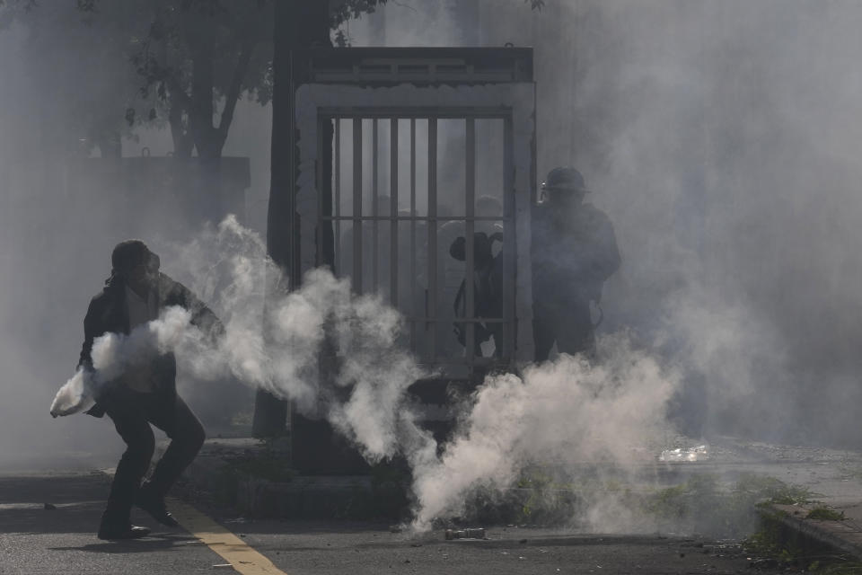 A retired army soldier throws back a tear gas canister toward riot police officers during a protest demanding better pay in Beirut, Lebanon, Thursday, Feb. 8, 2024. (AP Photo/Hussein Malla)