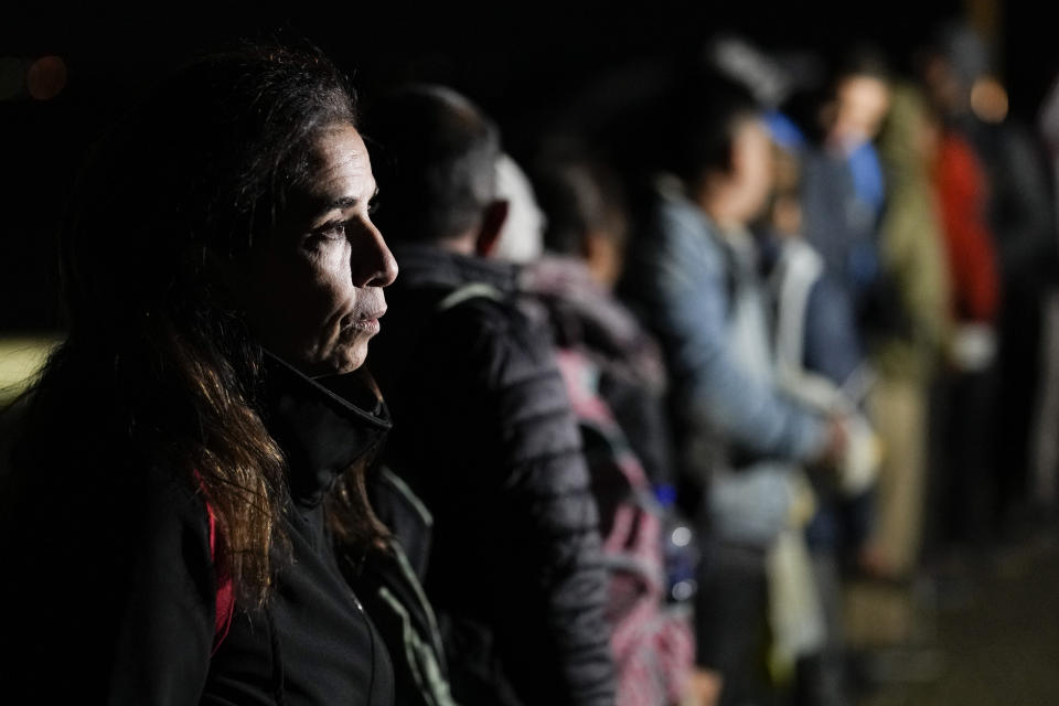 A woman from Cuba waits in line in the dark of night with other migrants.