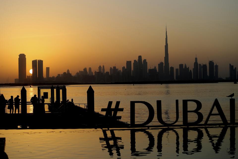 FILE - People enjoy the sunset with the view of city skyline and the world tallest tower, Burj Khalifa, in Dubai, United Arab Emirates, on Jan. 29, 2021. The FIFA World Cup may be bringing as many as 1.2 million fans to Qatar, but the nearby flashy emirate of Dubai is also looking to cash in on the major sports tournament taking place just a short flight away. (AP Photo/Kamran Jebreili, File)