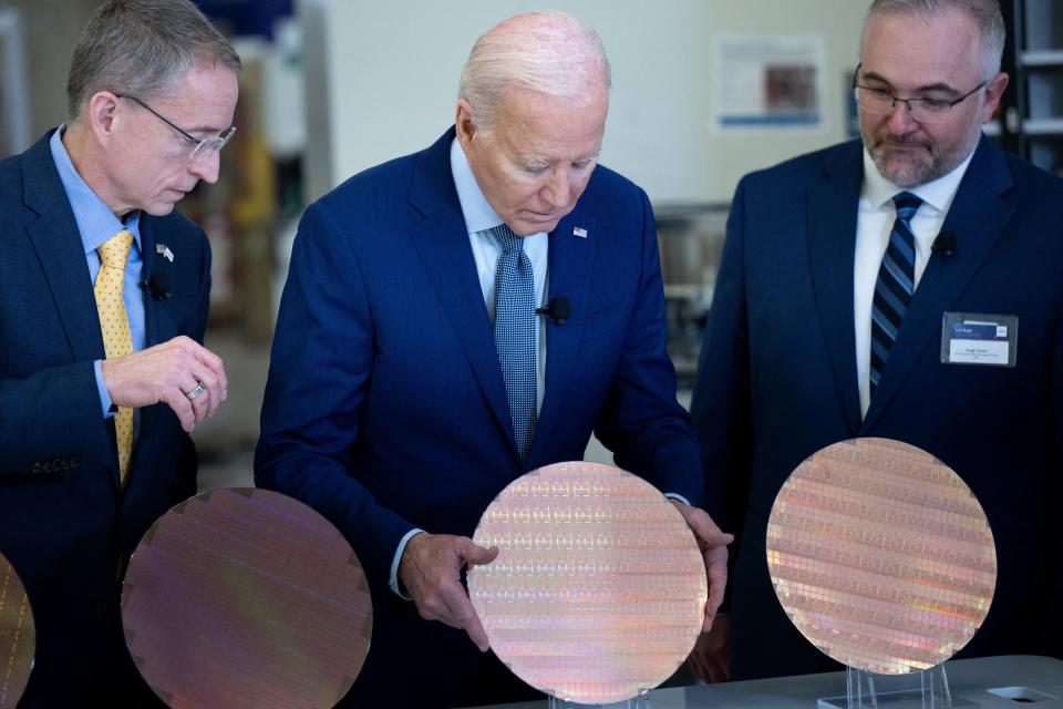 Intel CEO Pat Gelsinger (L) and Intel Factory Manager Hugh Green (R) watch as US President Joe Biden (C) looks at a semiconductor wafer during a tour at Intel Ocotillo Campus in Chandler, Arizona, on March 20, 2024.