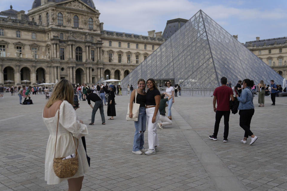 FILE - Tourists take pictures in front of the Pyramid in the Louvre Museum courtyard in Paris, France, on June 20, 2022. Travel to Europe might be an attractive option to travelers looking for a budget vacation in 2022. The dollar is strong this year, meaning your cash can go further on the continent. (AP Photo/Francois Mori)