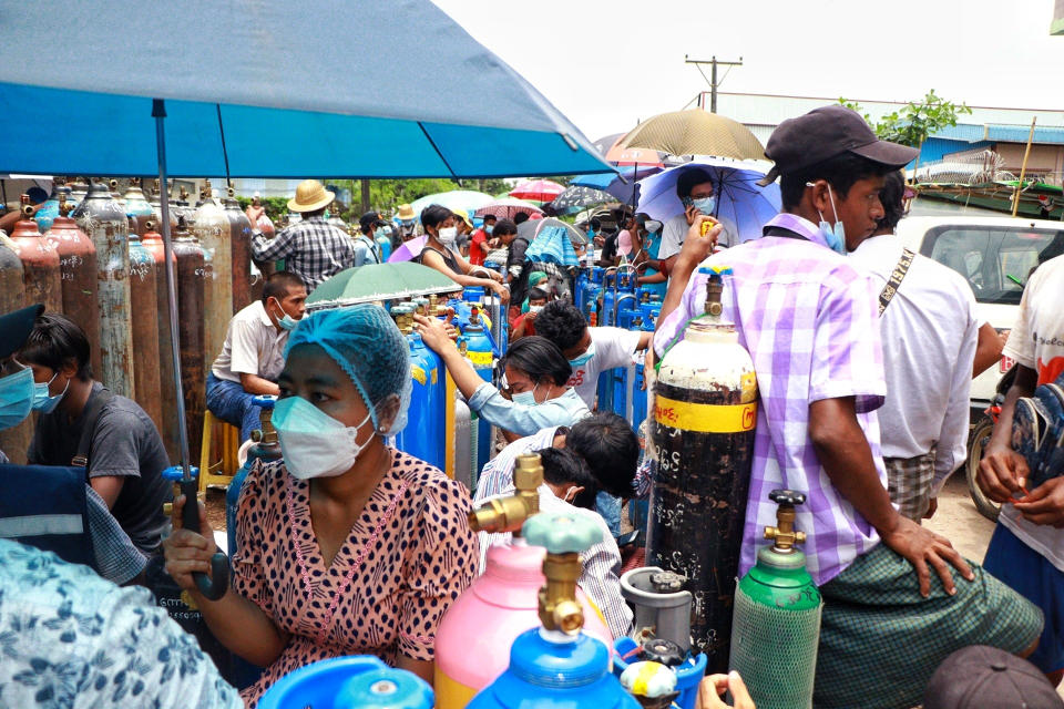 People wait in line next to oxygen tanks to be refilled outside the Naing oxygen factory at the South Dagon industrial zone in Yangon, Myanmar, Wednesday, July 28, 2021. Myanmar is currently reeling from soaring numbers of COVID-19 cases and deaths that are badly straining the country’s medical infrastructure. (AP Photo)
