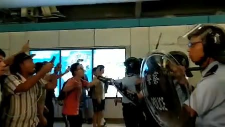 Social media video grab of anti-extradition bill demonstrators arguing with police after they were attacked by men in white t-shirts and face masks, at a train station in Hong Kong