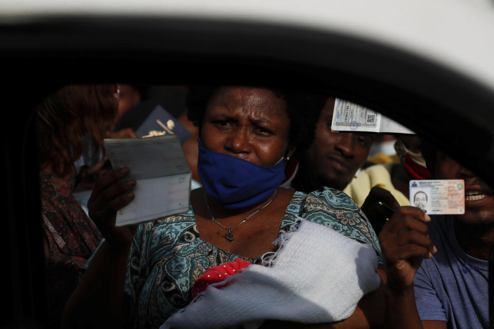 Haitians wave their passports shouting "Help, refugee," as they gather outside the U.S. Embassy in Port-au-Prince, Haiti, Friday, July 9, 2021. A large crowd gathered outside the embassy amid rumors on radio and social media that the U.S. will be handing out exile and humanitarian visas, two days after Haitian President Jovenel Moise was assassinated in his home. (AP Photo/Joseph Odelyn)