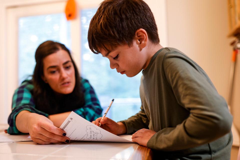 Amy Bearinger talks to her son Elliot, 8, as he works on math homework at their home in New Boston on Friday, Oct. 20, 2023.