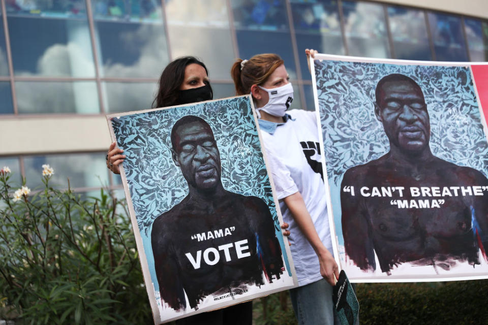 Farah Islam and Madison Campbell (L-R) hold pictures of George Floyd during the public viewing at the Fountain of Praise church on June 8, 2020 in Houston, Texas. Source: Joe Raedle/Getty Images