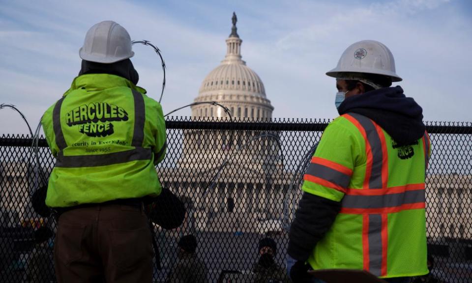 Workers install razor wire atop fencing outside the US Capitol ahead of Biden’s inauguration.