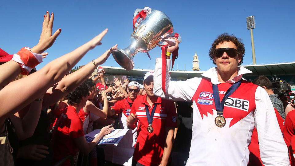 Shane Mumford is seen here with the AFL premiership trophy he won with the Swans in 2012.