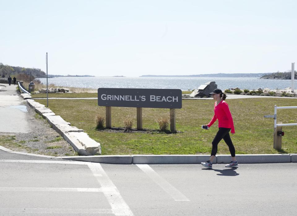 A woman walking past the Grinnell's Beach sign.