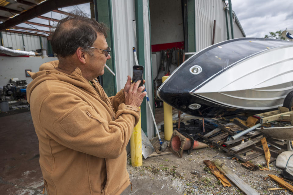 Hank Plauche takes photos of the damage to his overturned 24-foot, 1979 Excalibur boat at Scotty's Performance Boat & Marine, Thursday, April 11, 2024, in Slidell, La., after a tornado hit a day earlier. (Chris Granger/The Times-Picayune/The New Orleans Advocate via AP)