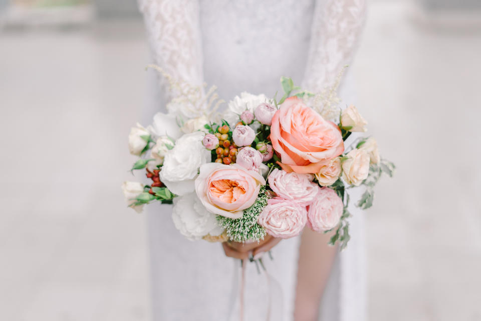 The bride holding soft wedding bouquet of roses, peonies and lisianthus, horizontal shot