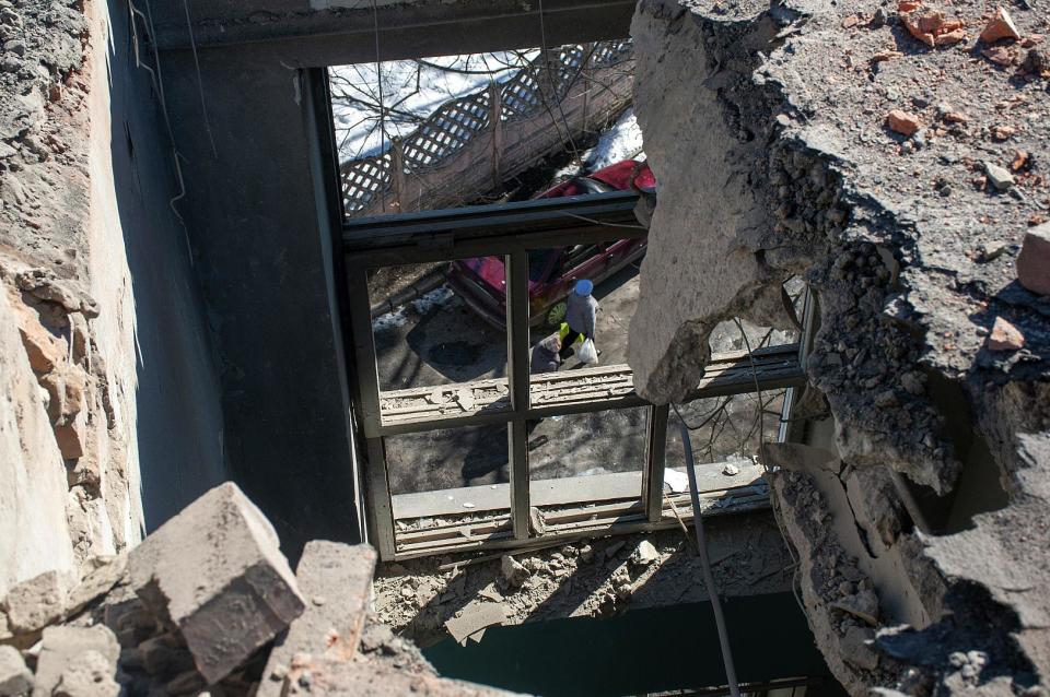 Durch das Dach eines von Granaten getroffenen Gebäudes in Charkiw kann man eine Frau auf der Straße sehen. 20. März 2022