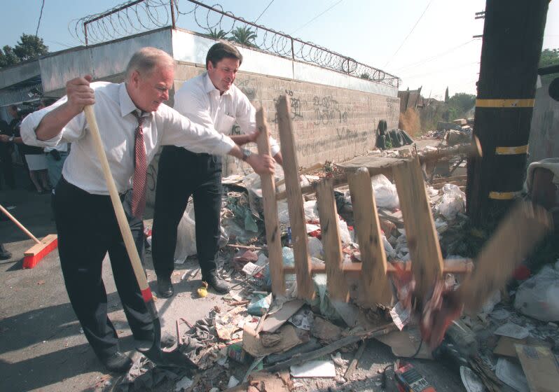 Los Angeles Mayor Richard Riordan (left) and Deputy Secretary of the United States Department of the Interior , John Garamendi (right), roll up their sleeves and pitch in to help cleanup an alley near 58th Street and Central Ave in South Los Angeles. The alley is the site of illegal dumping. Riordan and other officials were on hand to announce a city campaign against illegally dumped trash. Photo taken 9/19/96.Mandatory Credit: Anacleto Rapping/The LA Times