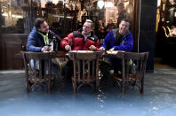 Men have a glass of wine at a flooded street in Venice, Italy November 15, 2019. REUTERS/Flavio Lo Scalzo