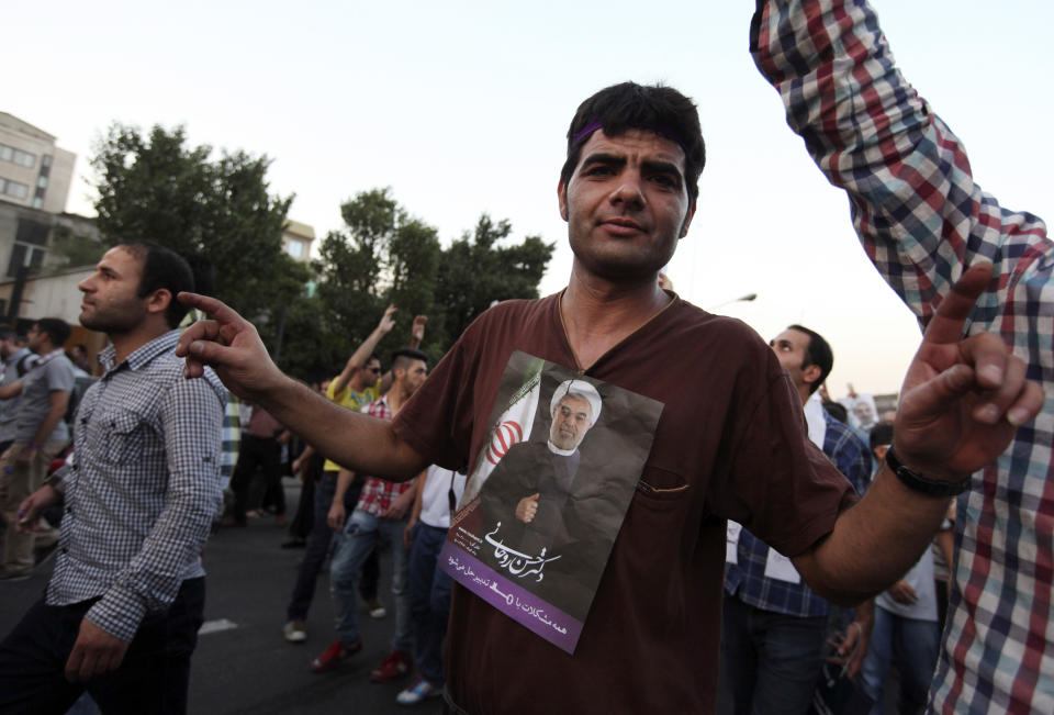 A supporter of Iranian presidential candidate Hassan Rouhani, shown in poster, attends a celebration gathering in Tehran, Iran, Saturday, June 15, 2013. (AP Photo/Vahid Salemi)