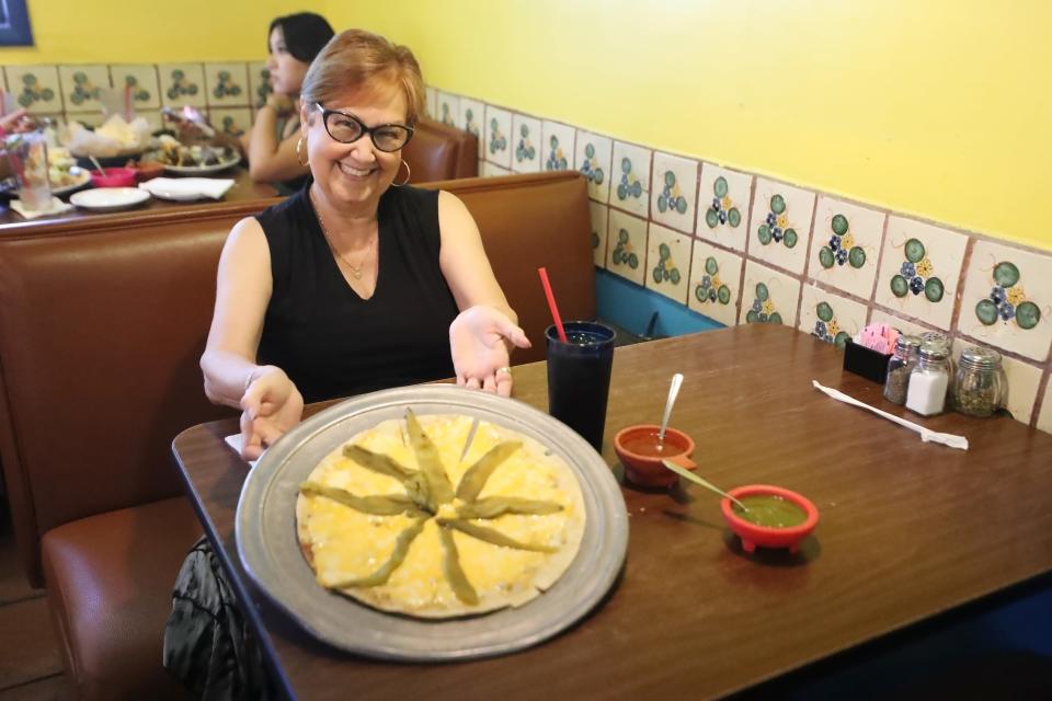 Julie Diaz shows off a cheese crisp with green chiles at Rosita's Place in Phoenix on Wednesday, July 19, 2023.