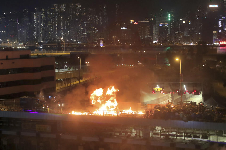 Protestors hurl molotov cocktails as armored police vehicles approach their barricades on a bridge over a highway leading to the Cross Harbour Tunnel in Hong Kong, Sunday, Nov. 17, 2019. A Hong Kong police officer was hit in the leg by an arrow Sunday as authorities used tear gas and water cannons to try to drive back protesters occupying a university campus and blocking a major road tunnel under the city's harbor. (AP Photo/Kin Cheung)