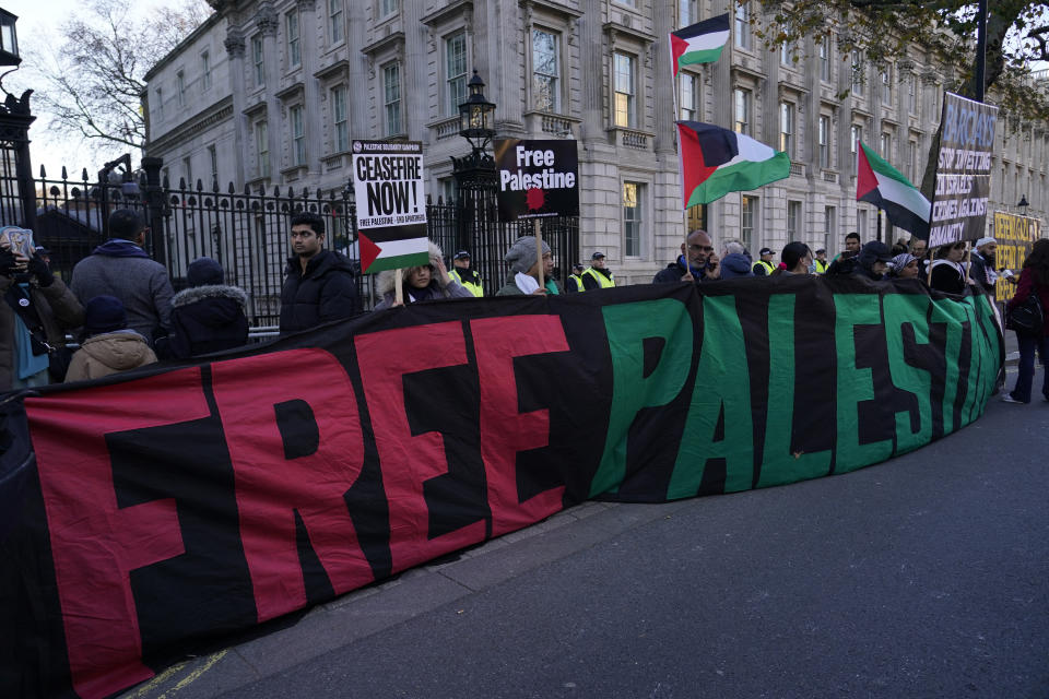 Protesters holds a large banner in front of the gates to Downing Street as they take part in a pro-Palestinian demonstration as they wend their way along Whitehall in London, Saturday, Nov. 25, 2023. (AP Photo/Alberto Pezzali)