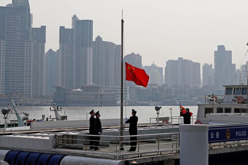 Police officer positions the Chinese national flag at half-mast along Huangpu river in Shanghai