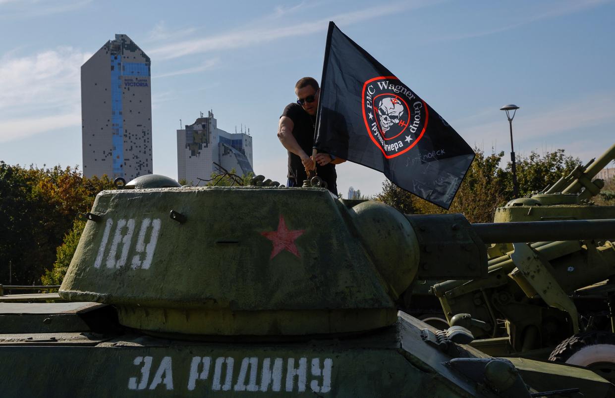 A man attaches a flag to Soviet-era tank at a makeshift memorial for Wagner chief Yevgeny Prigozhin (REUTERS)