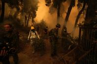 People try to extinguish the flames during a wildfire at Pefki village on Evia island, about 189 kilometers (118 miles) north of Athens, Greece, Sunday, Aug. 8, 2021. Pillars of billowing smoke and ash are blocking out the sun above Greece's second-largest island as a days-old wildfire devours pristine forests and triggers more evacuation alerts. (AP Photo/Petros Karadjias)