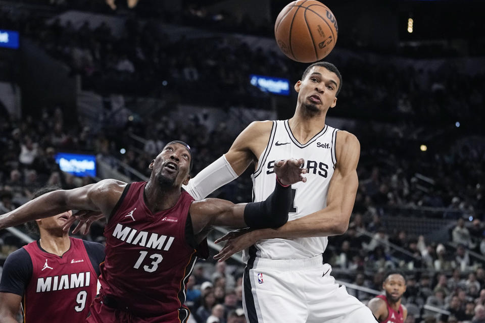 Miami Heat center Bam Adebayo and San Antonio Spurs center Victor Wembanyama chase a rebound during the first half of an NBA basketball game in San Antonio, Sunday, Nov. 12, 2023. (AP Photo/Eric Gay)