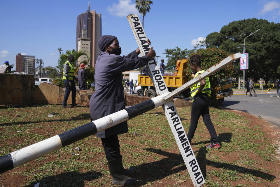 Nairobi county staff repair a street sign in downtown Nairobi, Kenya, Wednesday, June 26, 2024. Thousands of protesters stormed and burned a section of Kenya's parliament Tuesday to protest tax proposals. Police responded with gunfire and several protesters were killed. (AP Photo/Brian Inganga)