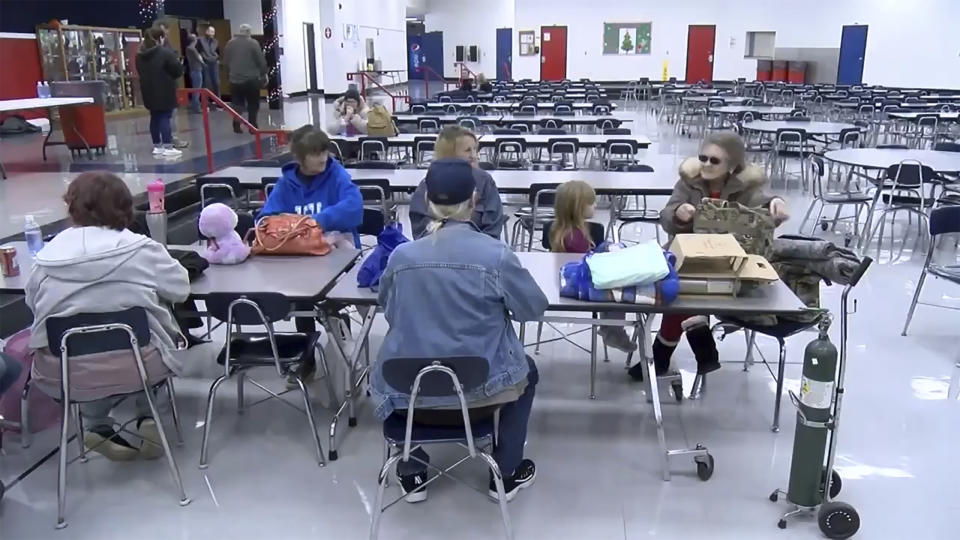 This image taken from video and provided by WTVQ shows people sitting at a table at Rockcastle Middle School being used as an evacuation center in Mt Vernon, Ky., Wednesday, Nov. 22, 2023. People were evacuated from a nearby town after a CSX train derailed Wednesday near Livingston, a remote town with about 200 people in Rockcastle County. CSX says two of the 16 cars that derailed carried molten sulfur, which caught fire after the cars were breached. (WTVQ via AP)