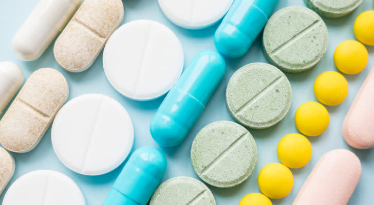 rows of pills on a table representing pharmaceutical stocks. EVAX stock