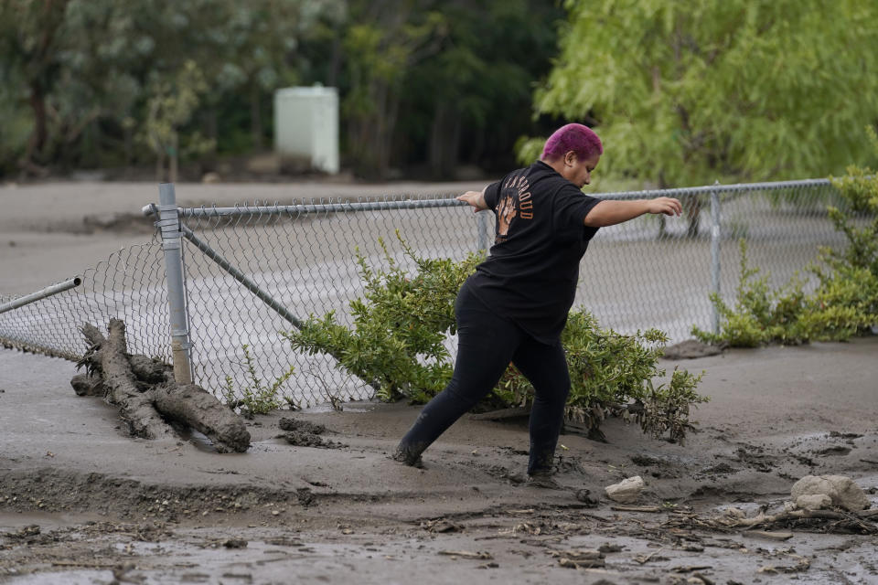 Perla Halbert walks through the mud along her driveway in the aftermath of a mudslide Tuesday, Sept. 13, 2022, in Oak Glen, Calif. Cleanup efforts and damage assessments are underway east of Los Angeles after heavy rains unleashed mudslides in a mountain area scorched by a wildfire two years ago. (AP Photo/Marcio Jose Sanchez)