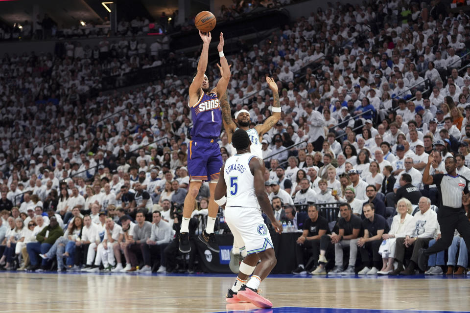 Phoenix Suns guard Devin Booker (1) shoots over Minnesota Timberwolves guards Nickeil Alexander-Walker, back, and Anthony Edwards (5) during the first half of Game 2 of an NBA basketball first-round playoff series Tuesday, April 23, 2024, in Minneapolis. (AP Photo/Abbie Parr)