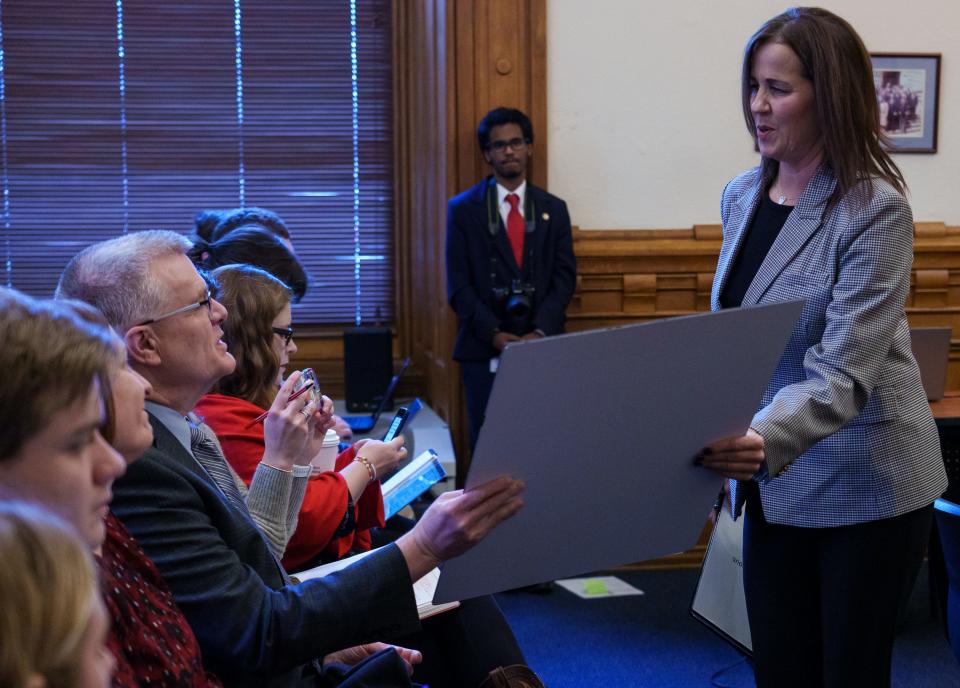 Julie West, of La Porte, Indiana, grabs a poster from John Doherty, an athletic trainer, after testifying Monday, Feb. 6, 2023, during a Senate Family and Children Services committee meeting on Senate Bill 369, which requires AEDs on the premise of sporting events. West lost her son, Jake, to sudden cardiac arrest in 2013.