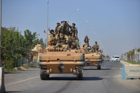 Members of Syrian National Army, known as Free Syrian Army, wave as they drive to cross into Syria near the Turkish border town of Ceylanpinar