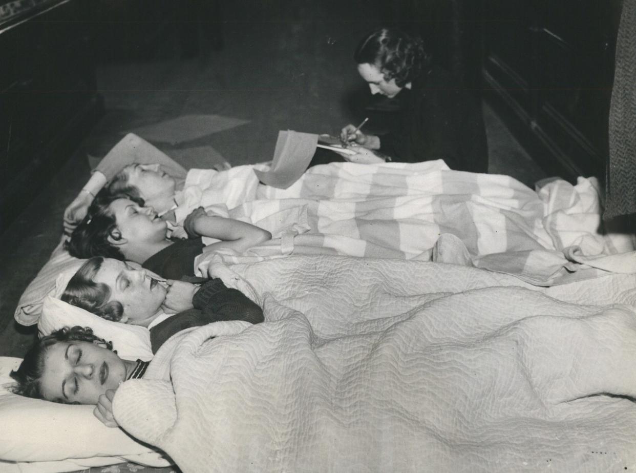 A group of women from left to right, Helen Shereda, Marie Smith, Loraine Berels, Faye House, all sleeping, and Rose Polinski, writing a letter to her sweetheart on wrapping paper while participating in a sit-down strike at the F. W. Woolworth Co. in Detroit during a strike on March 2, 1937.