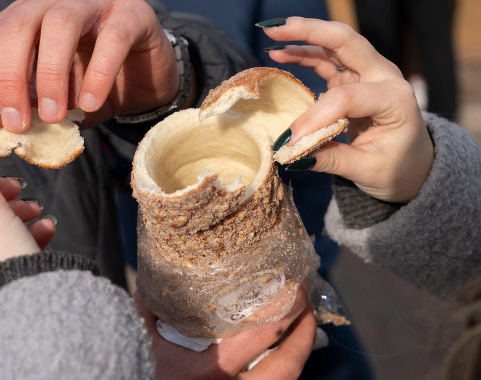 Visitors to the Christkindlmarkt Christmas market in Carmel tear into a “chimney bread” Wednesday, Nov. 22, 2023. The market offers a variety of authentic food and drinks from Germany or German-speaking countries.