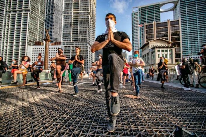Protesters perform yoga exercises while blocking the Brickell Avenue Bridge in downtown Miami on Saturday, June 27, 2020.